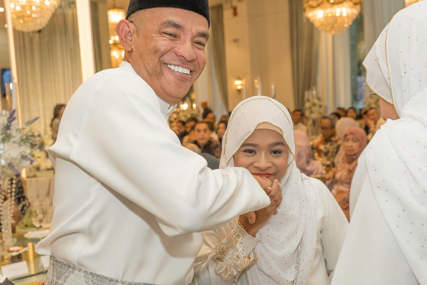 Wedding guests in traditional white and black attire sharing joyful moments during a celebration.