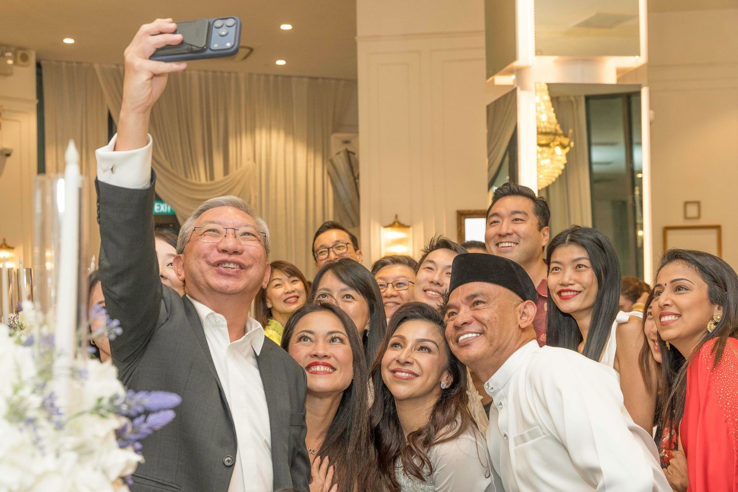 Wedding guests celebrating and taking photos together at reception venue.