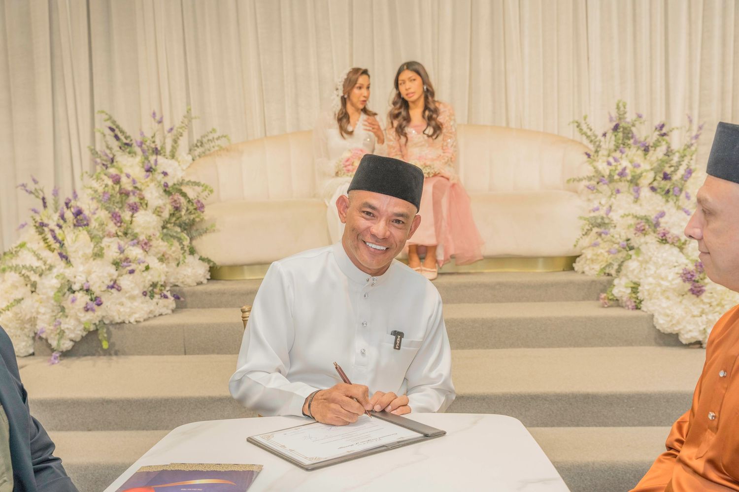 Wedding ceremony guests seated in rows with floral decorations in an elegant indoor venue.