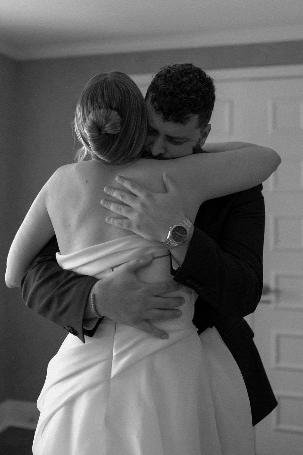 Intimate black and white photo of a couple embracing during a wedding first look moment.
