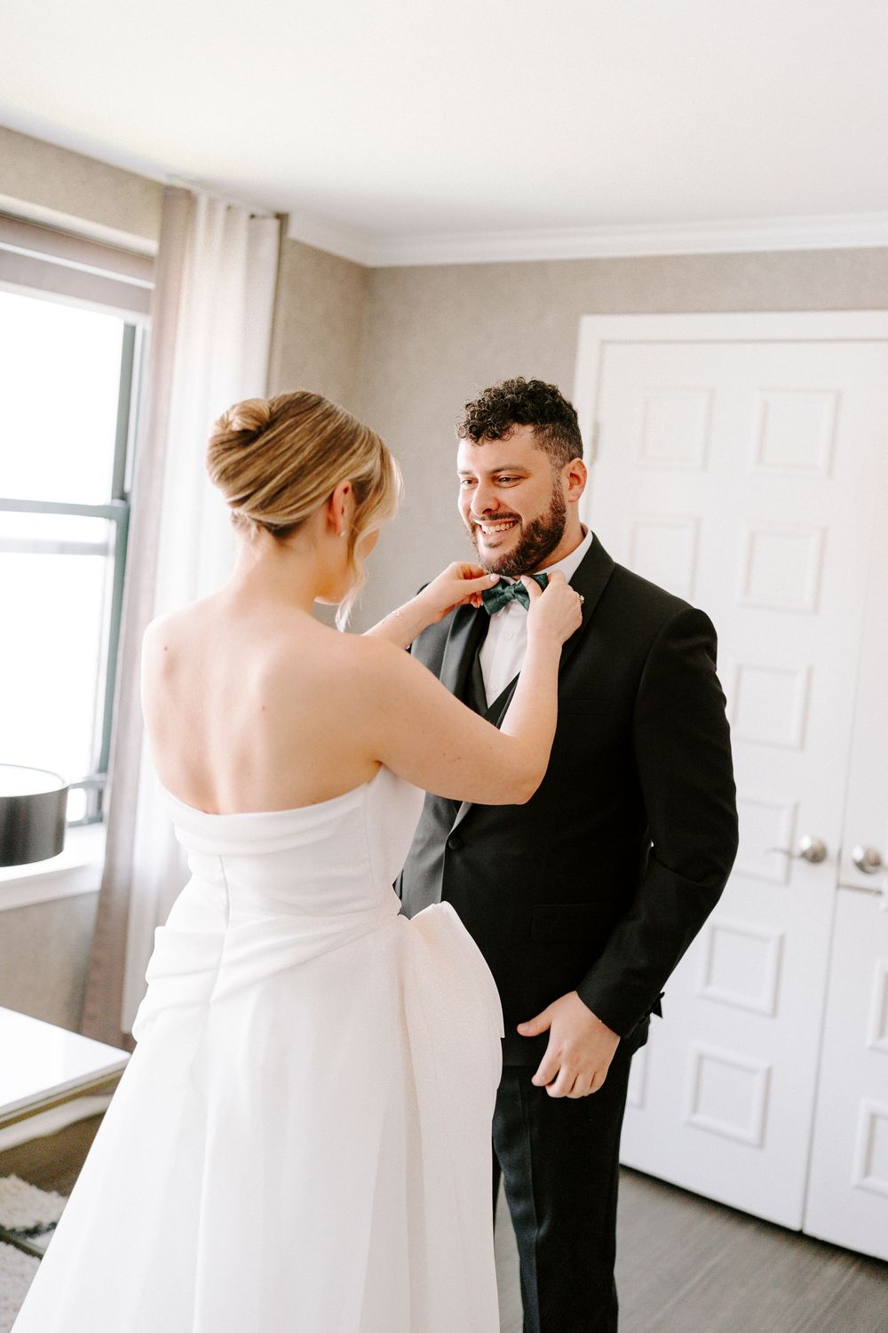 Candid wedding moment showing joyful reactions during a first look in a bright indoor setting.