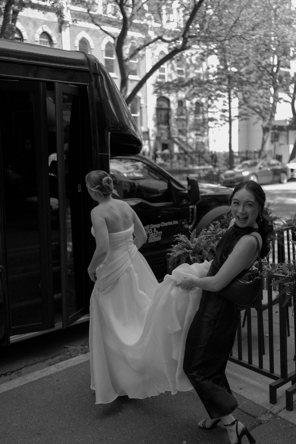 Black and white photo of a couple dancing playfully on a city street.