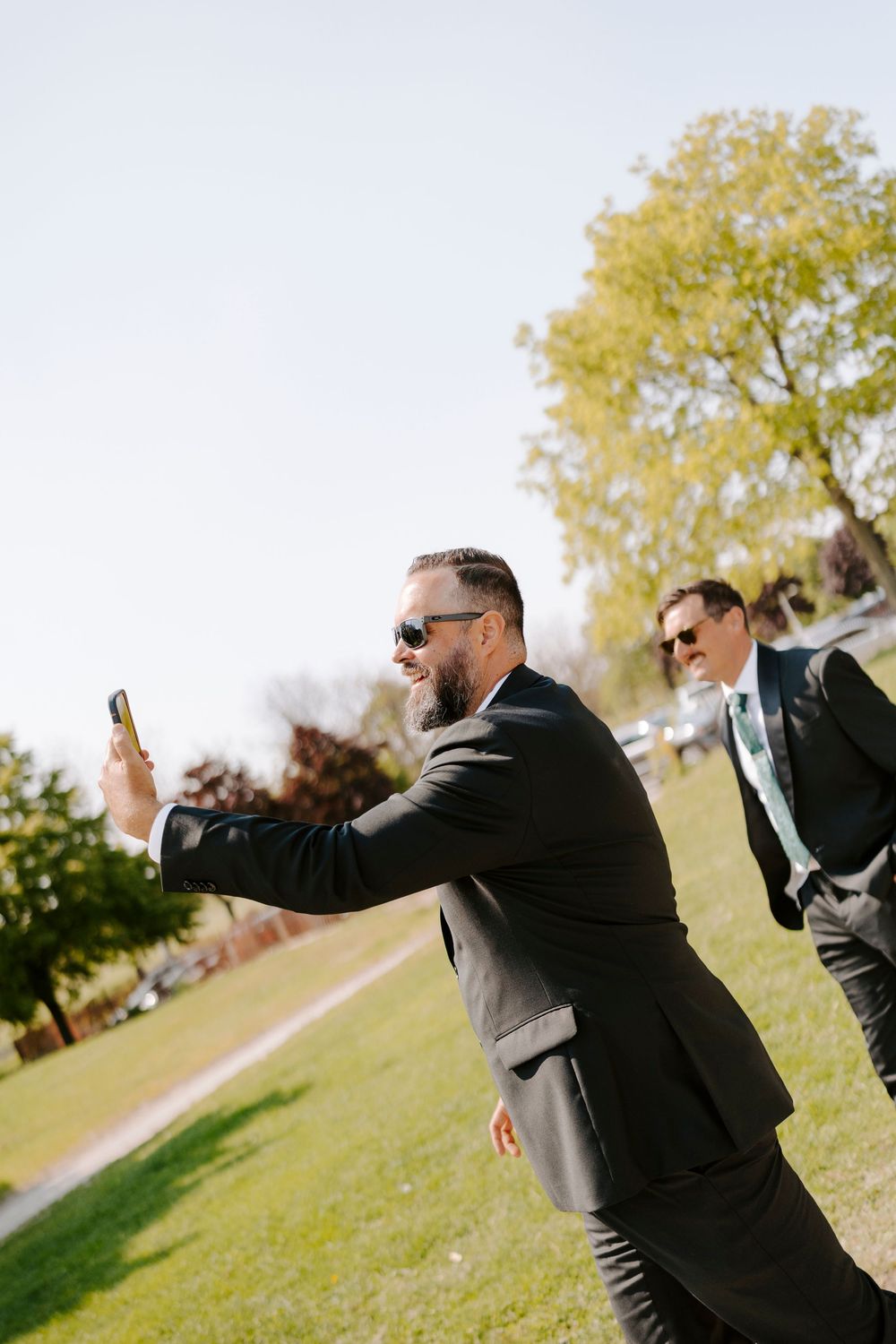 A series of photos showing a person in a black suit making dramatic poses in a grassy outdoor setting.