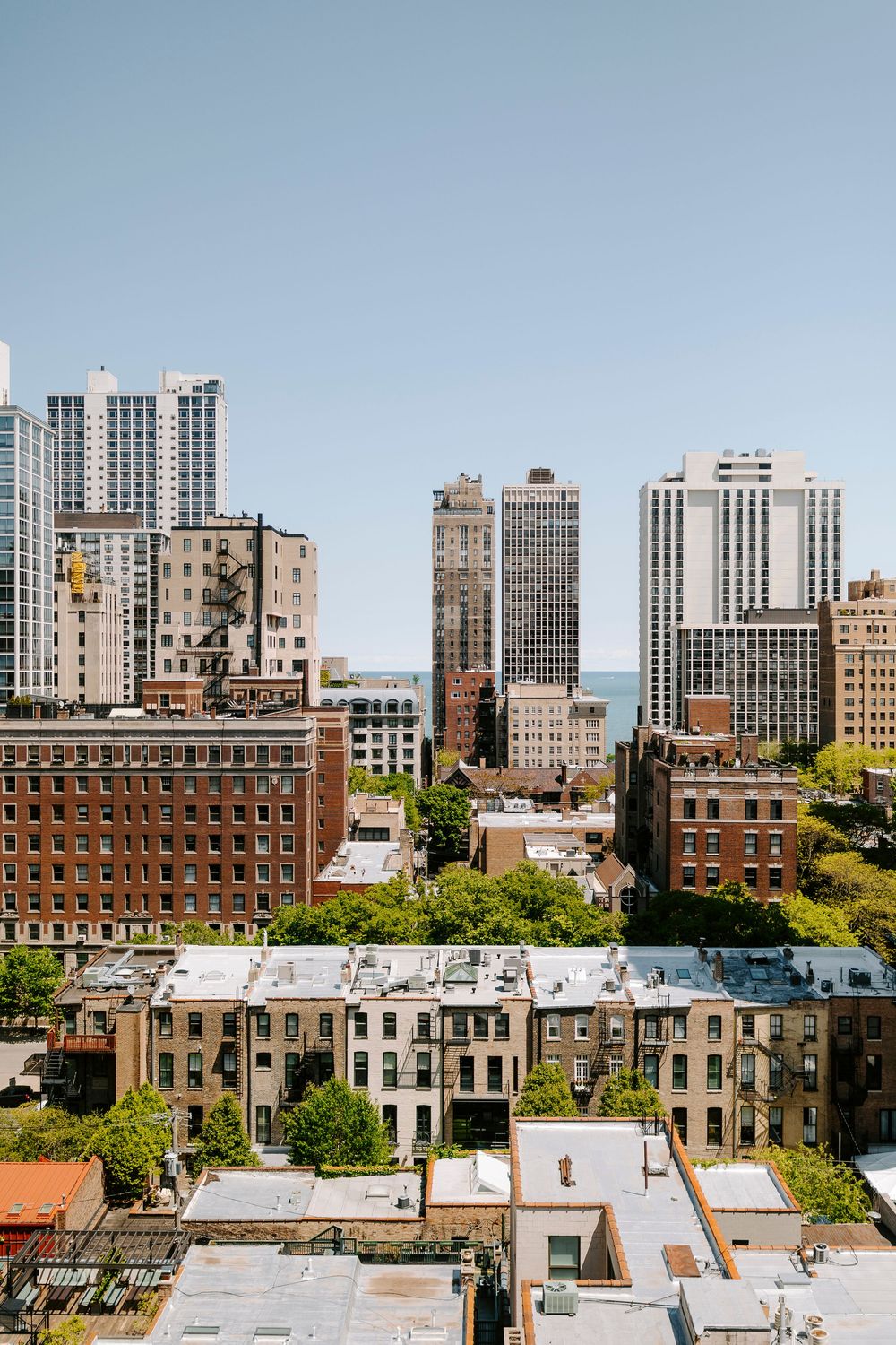 Urban skyline view of brick buildings and high-rises against a blue sky in a city neighborhood.