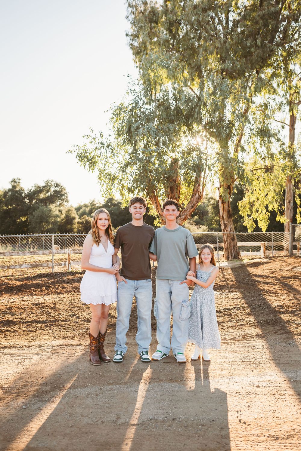 Family poses together in a golden sunset among eucalyptus trees in a natural outdoor setting.