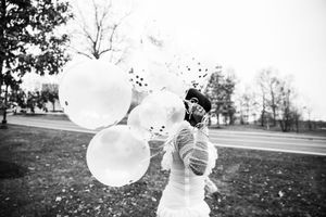 Black and white series capturing joyful moments with confetti-filled balloons in an outdoor setting.