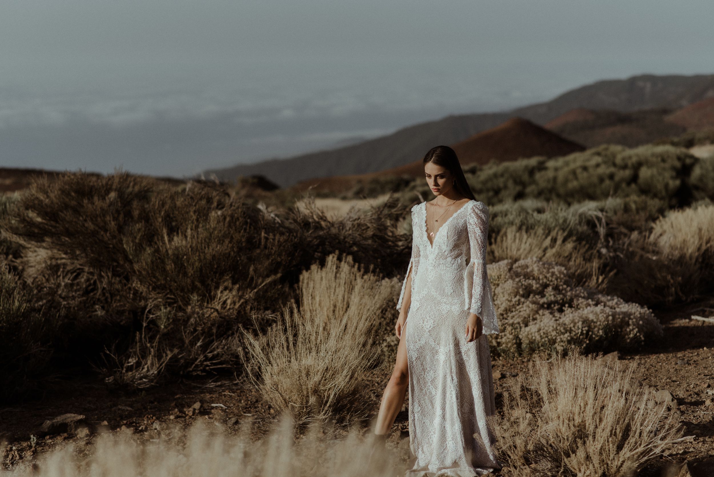 White wedding dress silhouetted against desert mountains and sage brush.