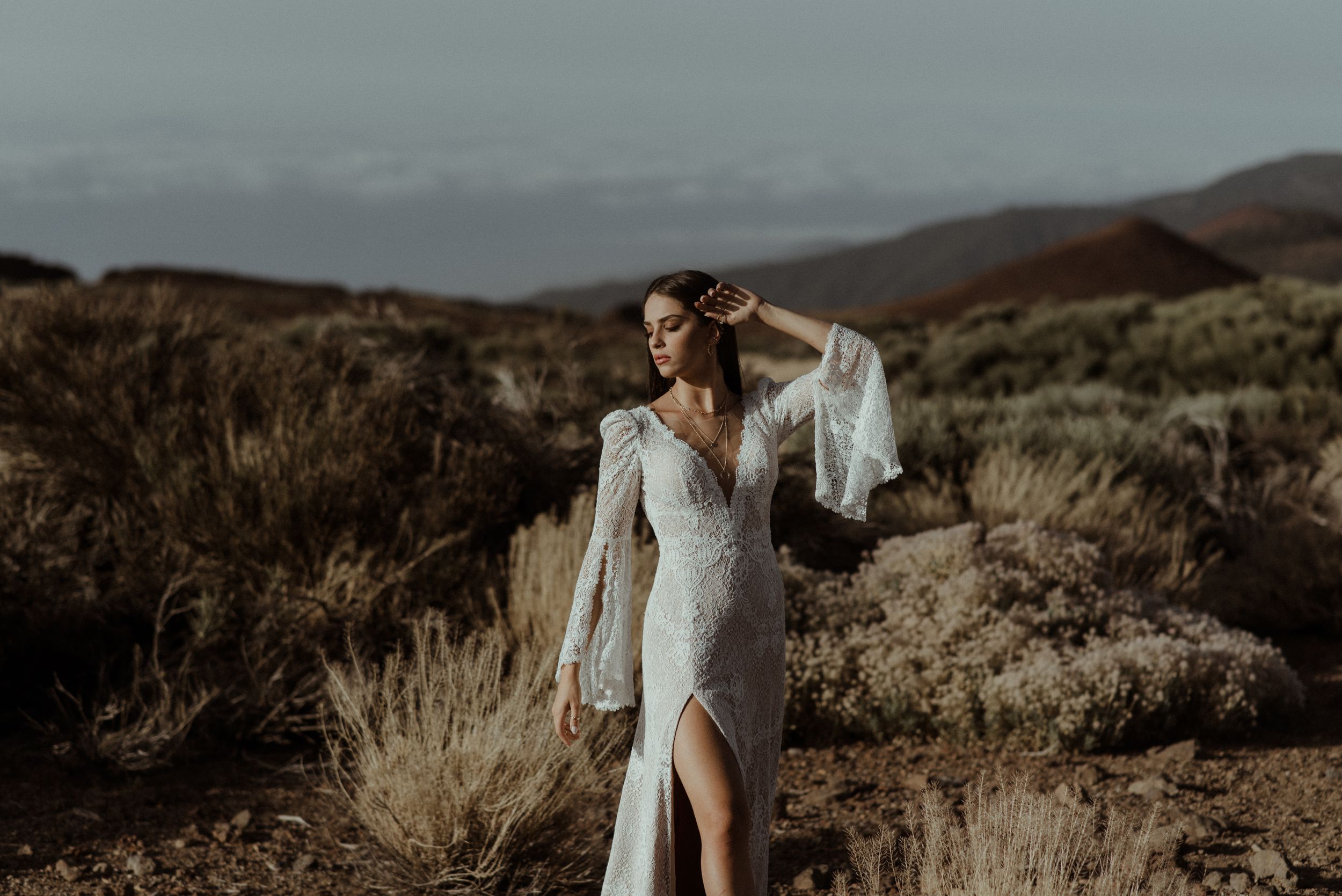 Elegant bridal gown with flowing sleeves captured in desert wilderness setting.