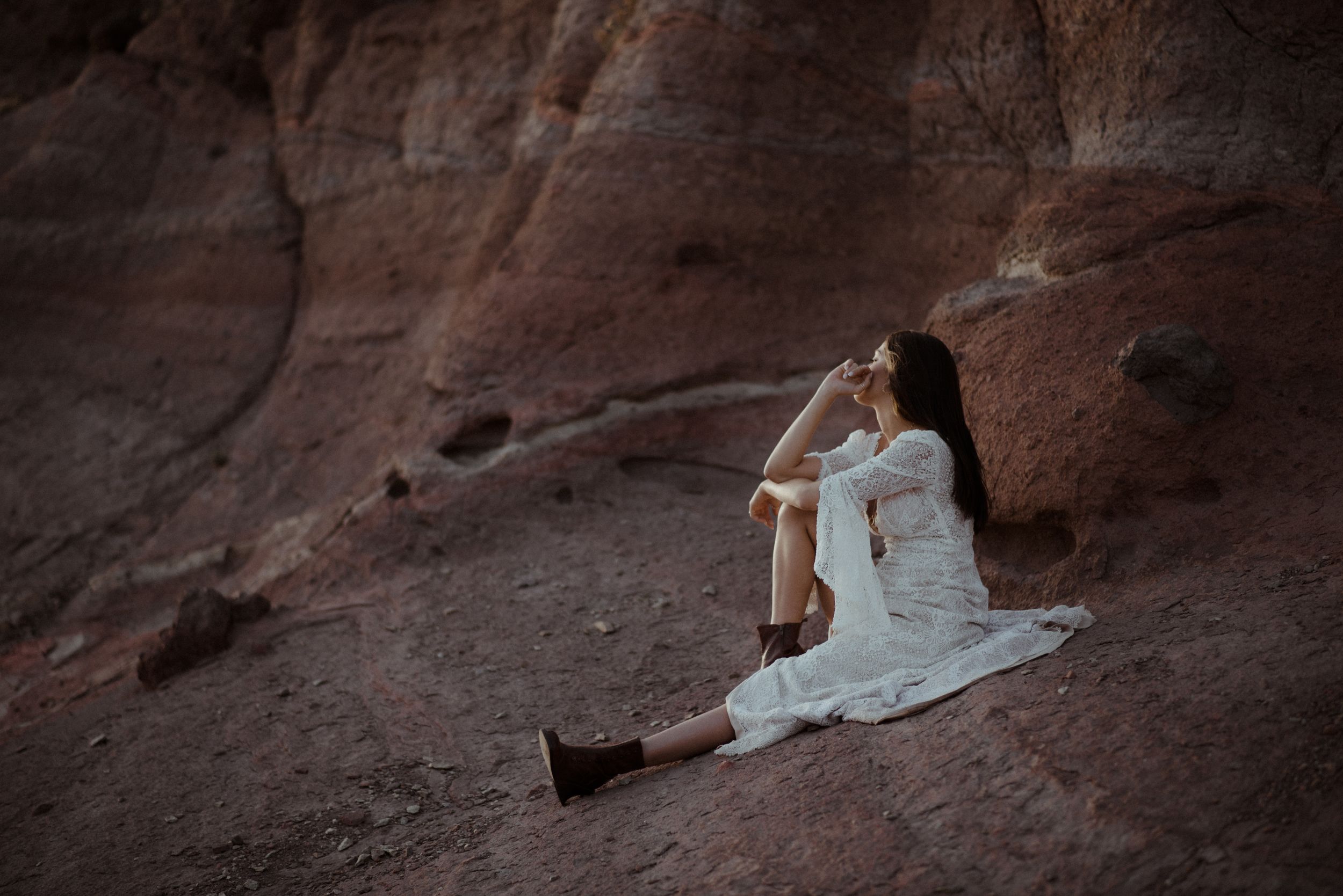 A dreamy white lace gown photographed against red rock formations at sunset.