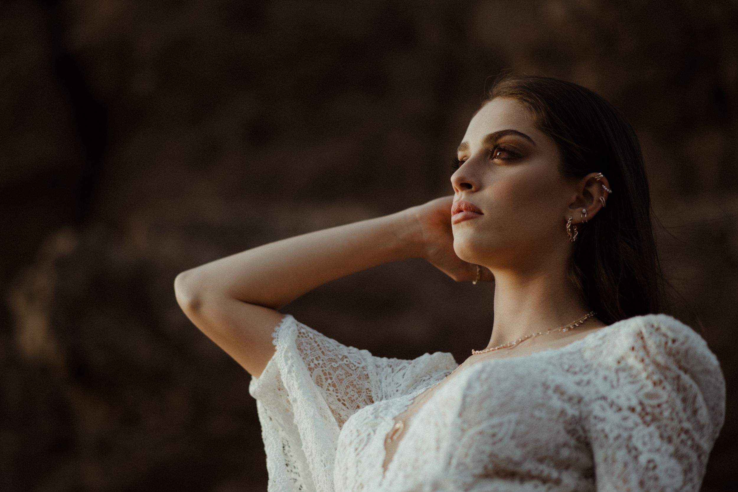 Soft golden light illuminates delicate lace details against rocky terrain.