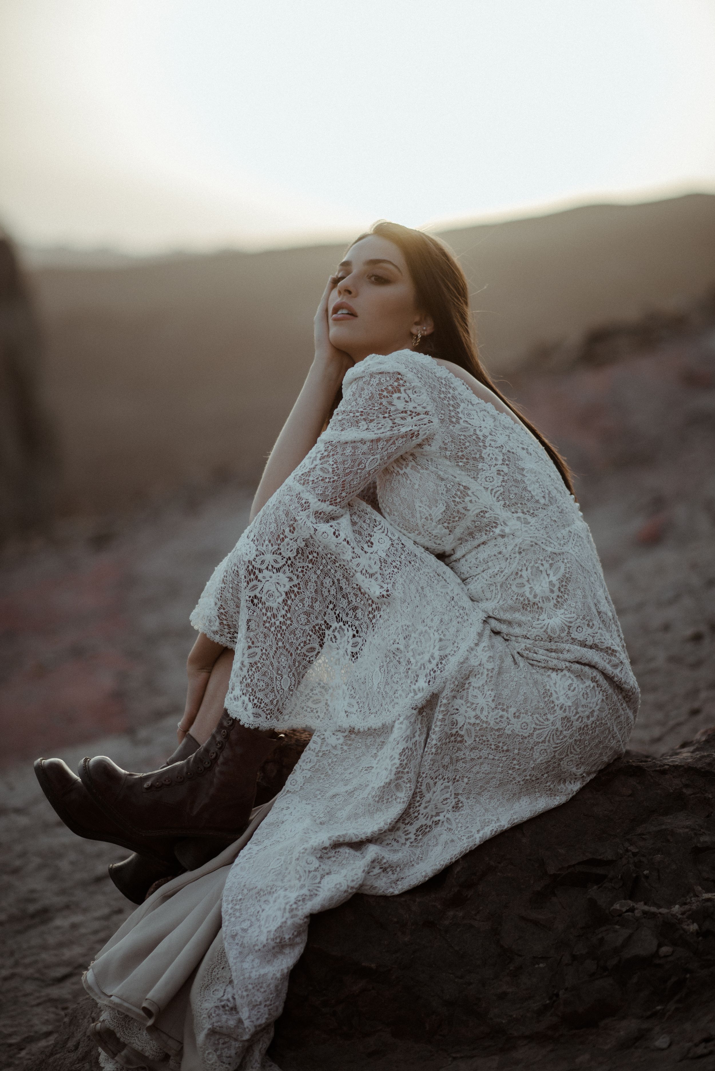 Vintage-inspired white lace dress paired with dark boots in desert setting.