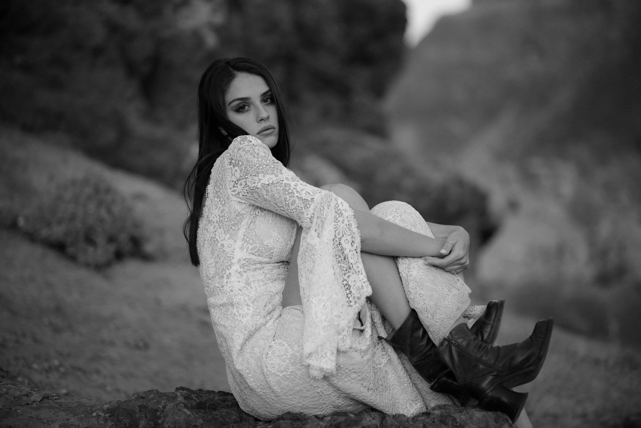 Monochrome portrait showcasing romantic white lace dress styled with rugged boots.