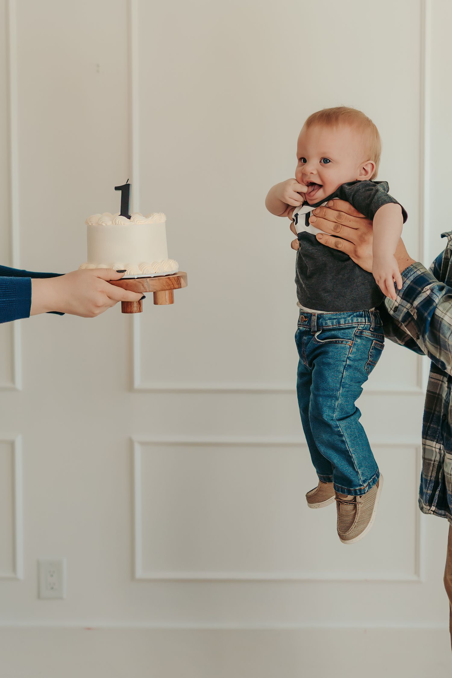 High angle view of a toddler in white dress sitting on floor with cake and scattered flour during a cake smash session.