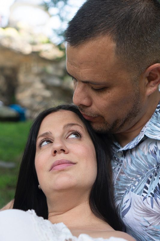 A romantic outdoor portrait of a couple sharing an intimate moment near stone walls.