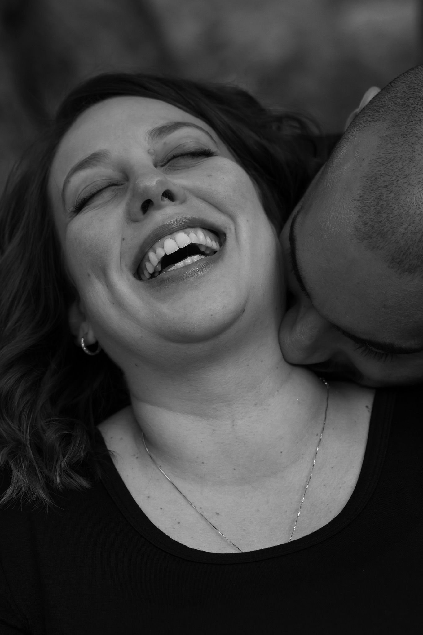 Close-up black and white portrait capturing joyful laughter during intimate moment.