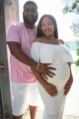 Hands holding an ultrasound photo against pink and white clothing.
