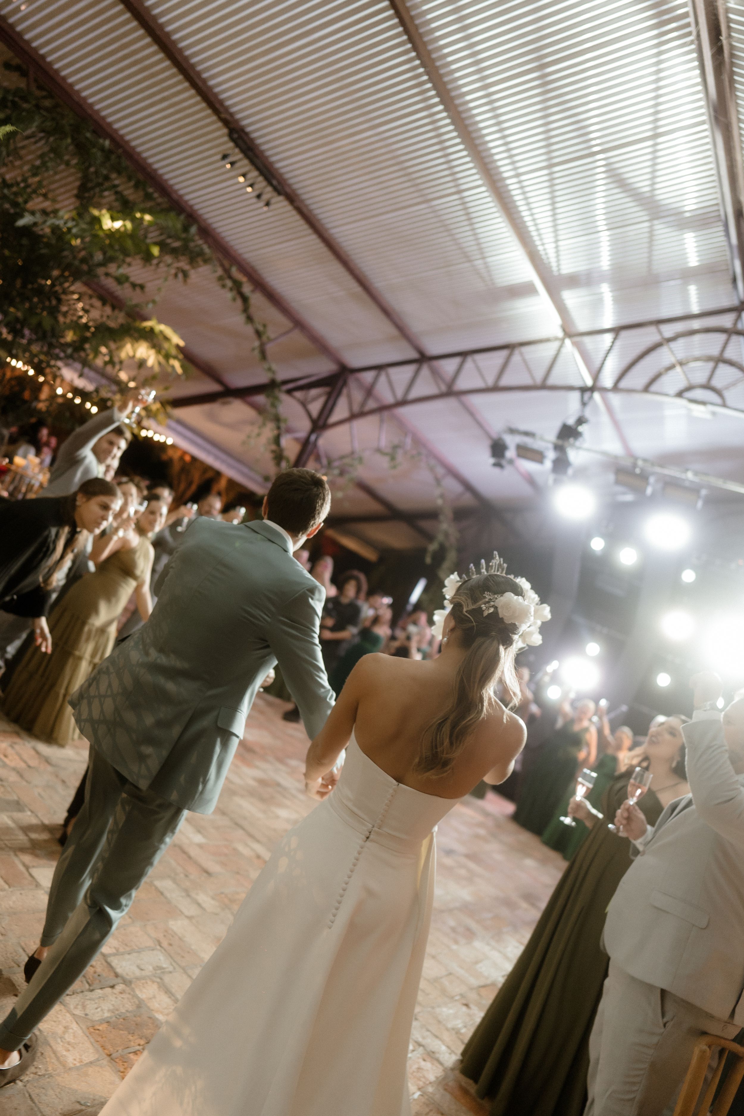 Newlyweds dancing at their reception under decorative lighting.