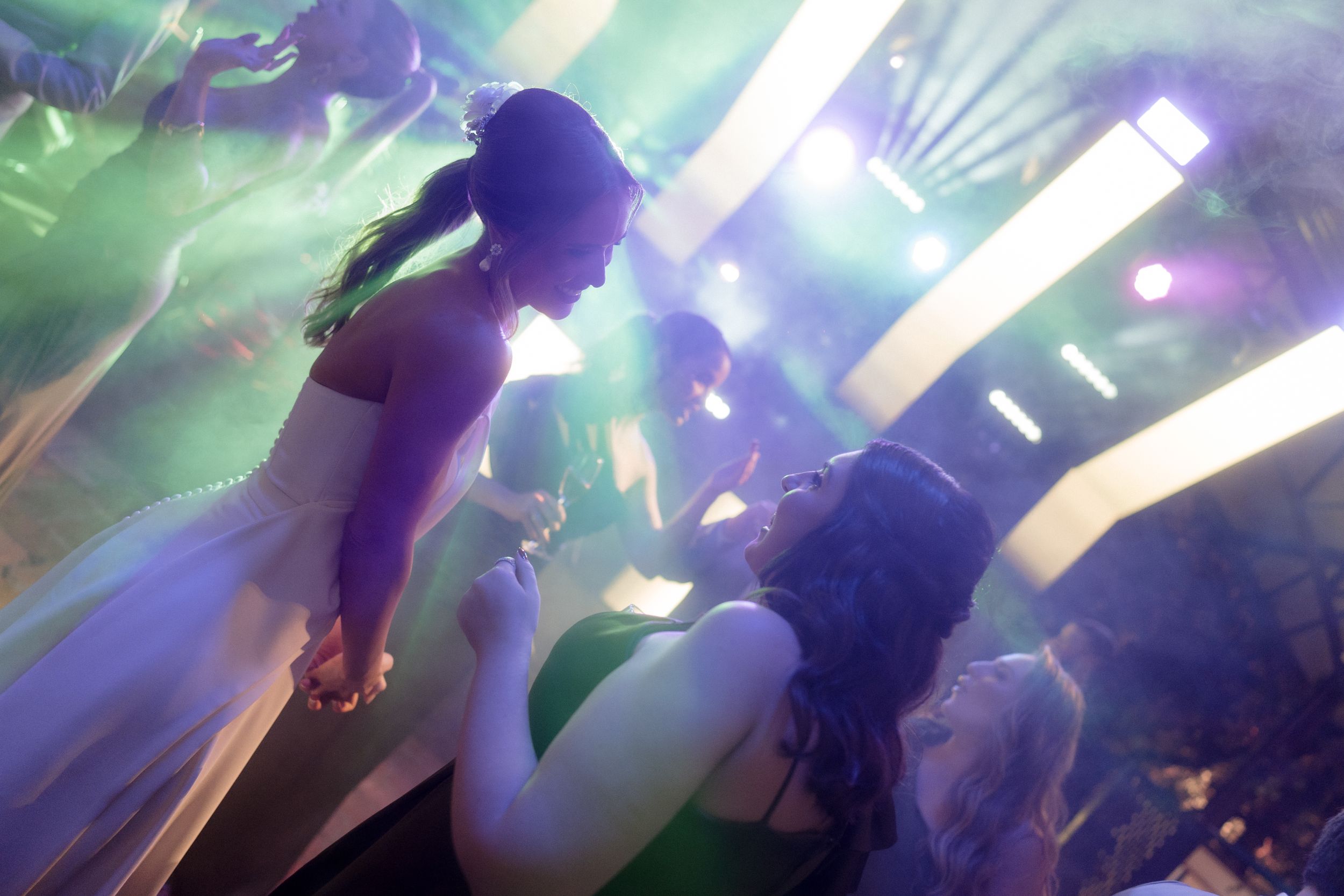 People dancing in a colorful club atmosphere with light effects.