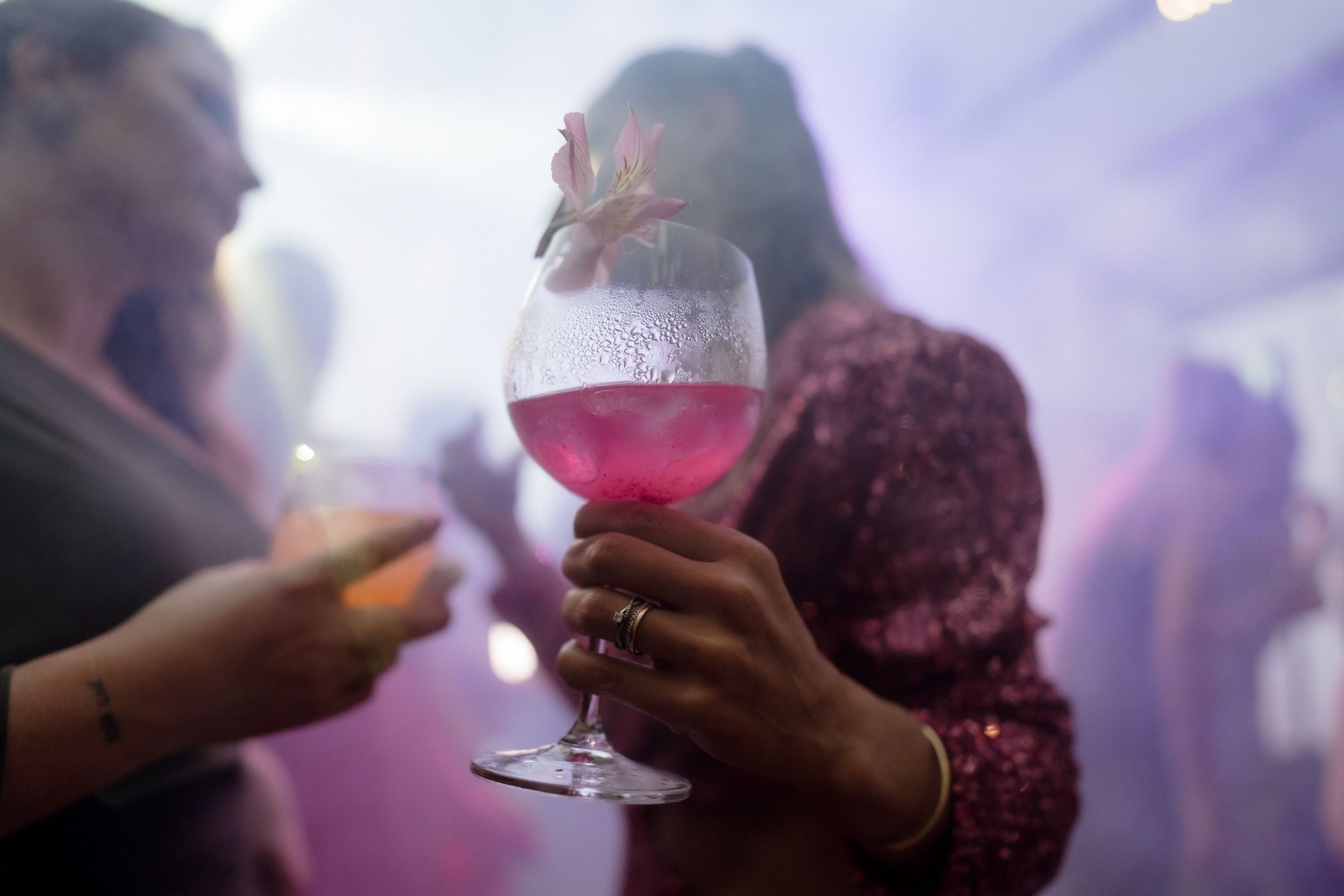 People holding wine glasses at an evening celebration.