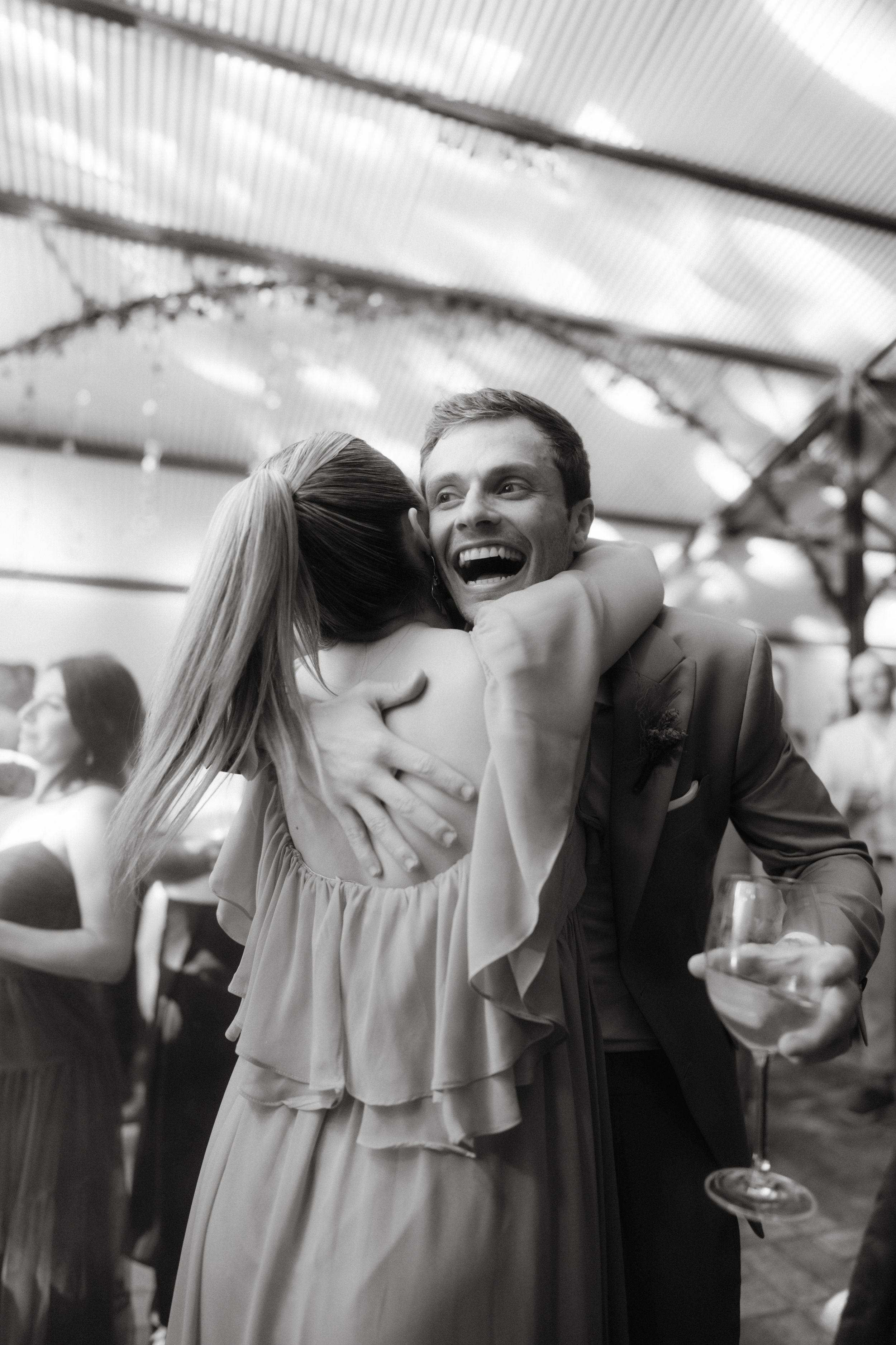 Black and white photo of guests dancing and laughing at a celebration.