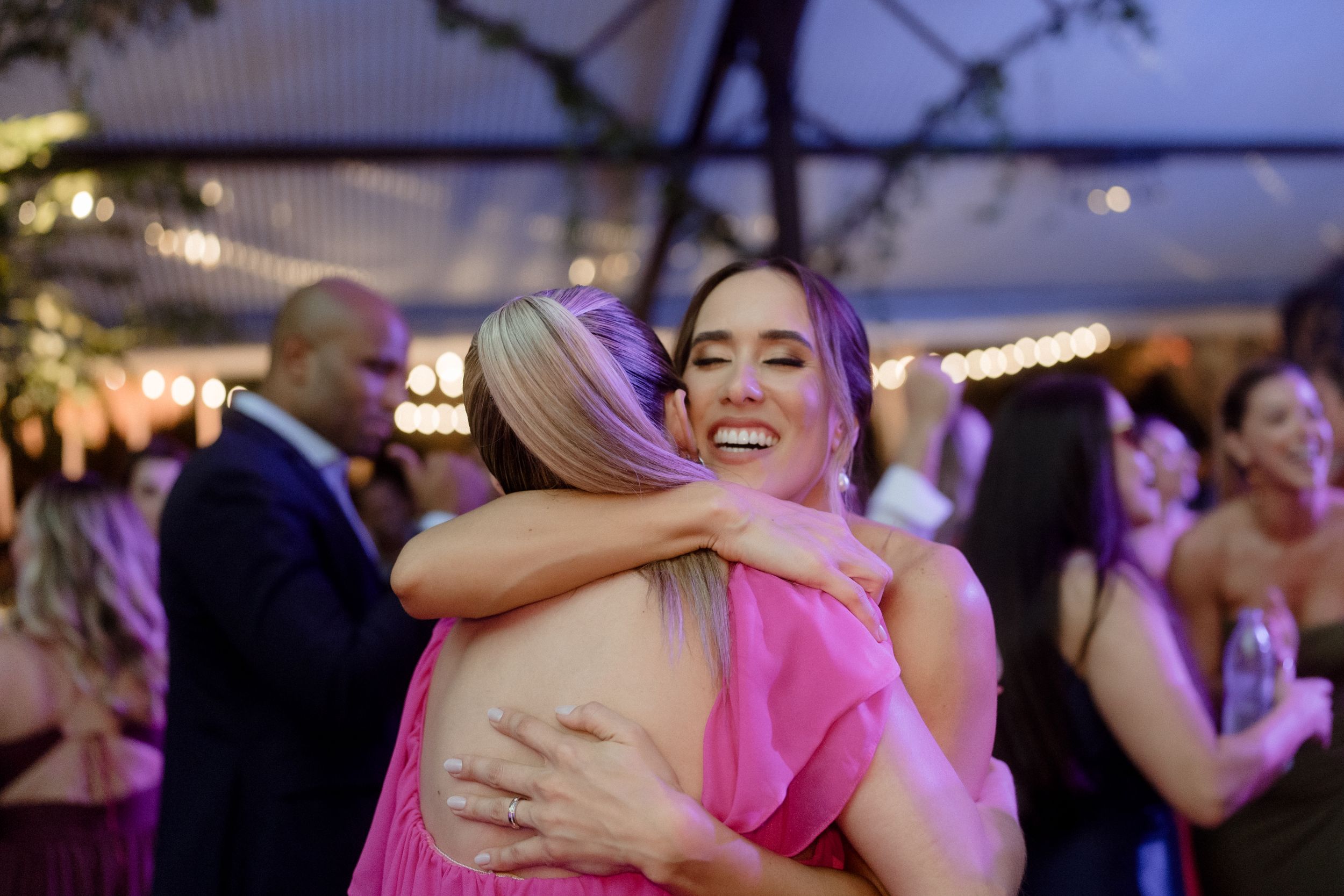 Wedding guests embracing and dancing during reception festivities.