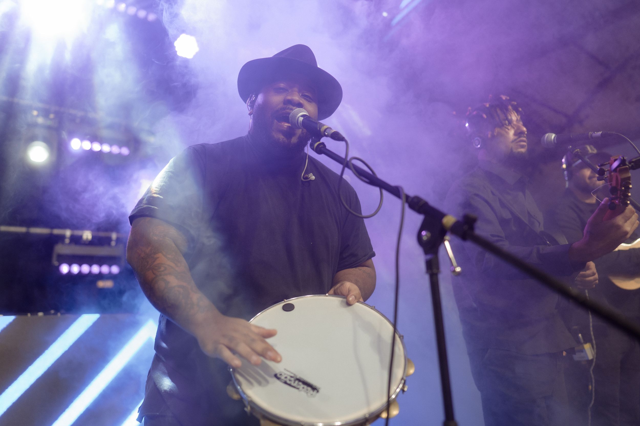 Band performing on stage with dramatic purple lighting and fog effects.