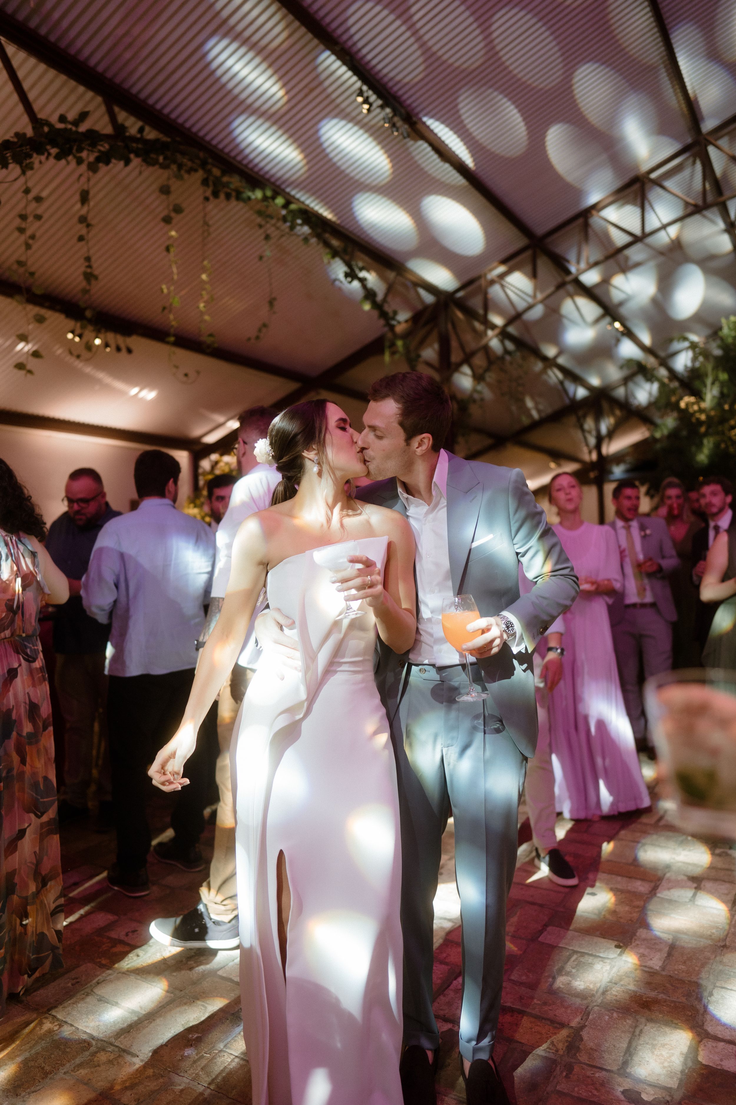 Wedding reception dance floor with guests under dramatic lighting and decorative ceiling.