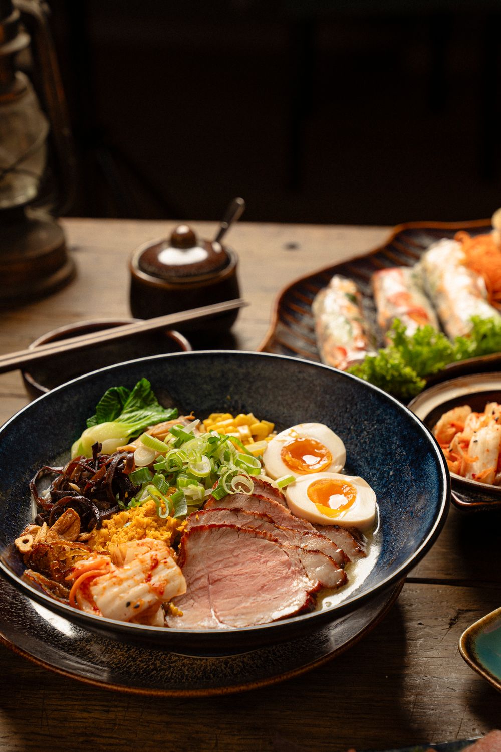 Ramen bowl with sliced meat, soft boiled eggs, noodles and vegetables in a rich broth.