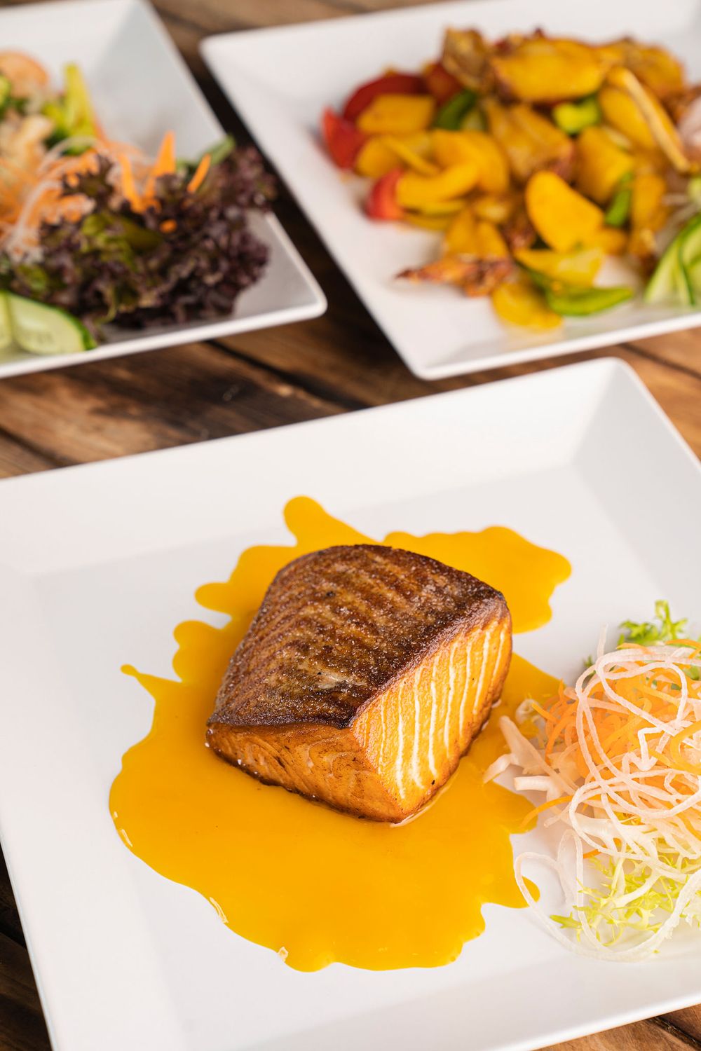 Grilled salmon fillet with orange sauce and shredded daikon radish garnish on white plate.