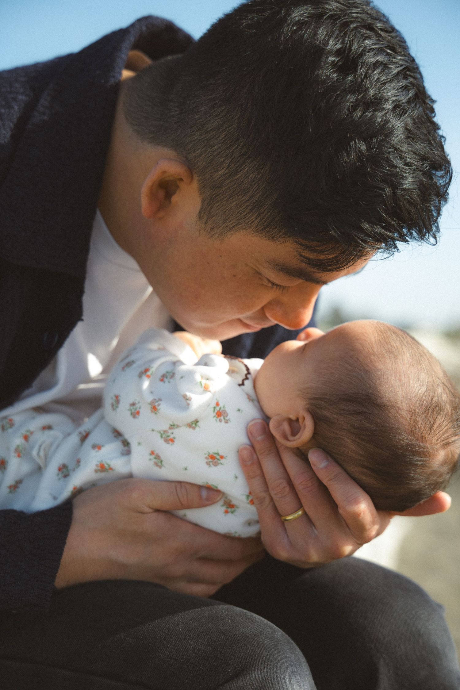 Dad holding his newborn baby girl and cuddling her tenderly during a family photoshoot in Vancouver, BC by a Vancouver Family Photographer.