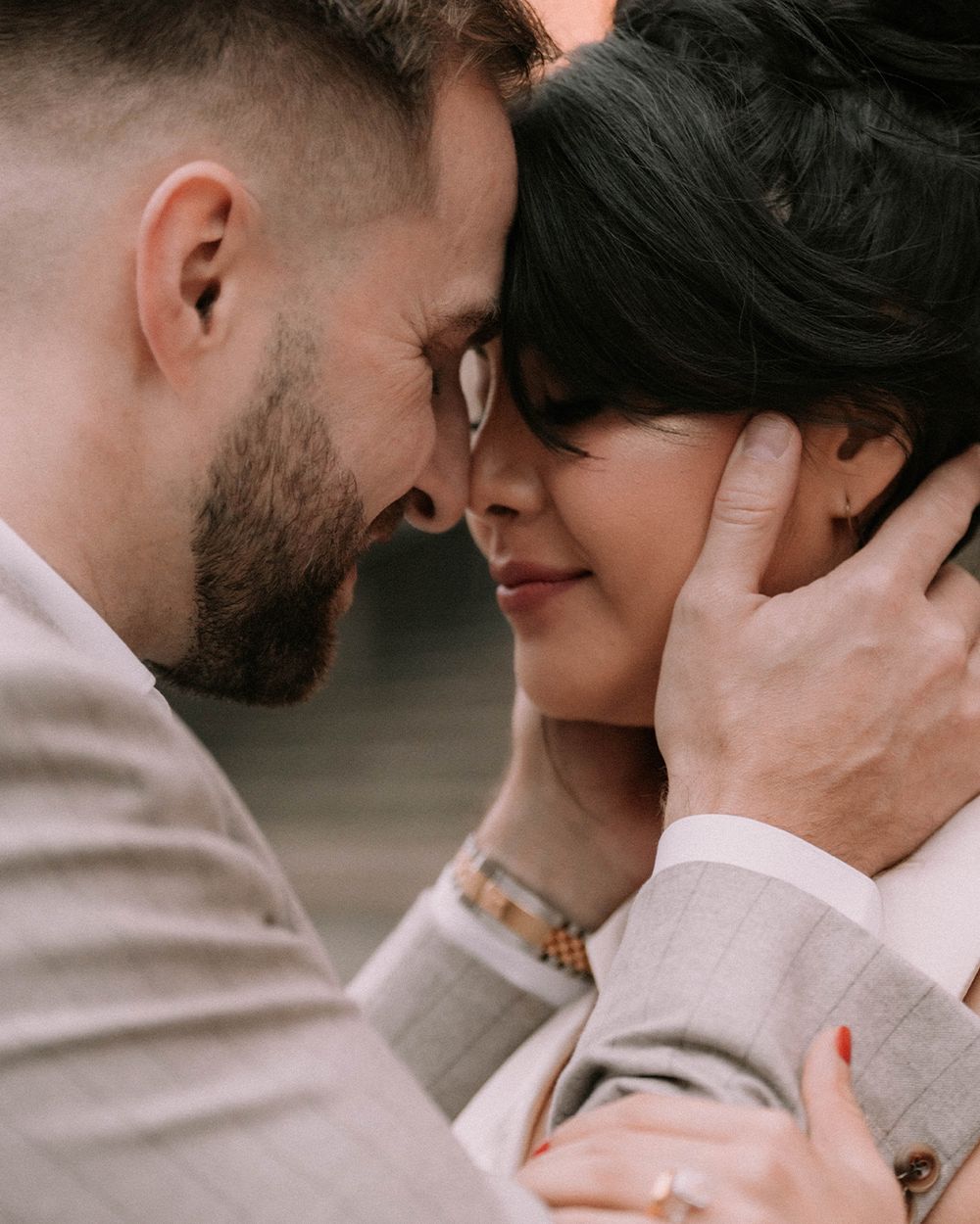 A couple shares an intimate moment, foreheads touching, as a man gently cups a woman's face in his hands.