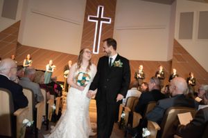 Wedding guests gather and dance during an indoor reception with ambient lighting.