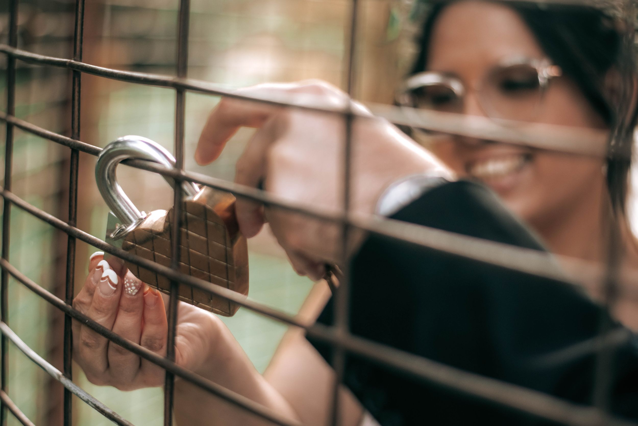Artistic close-up shot of hands placing a lock on metal bars.