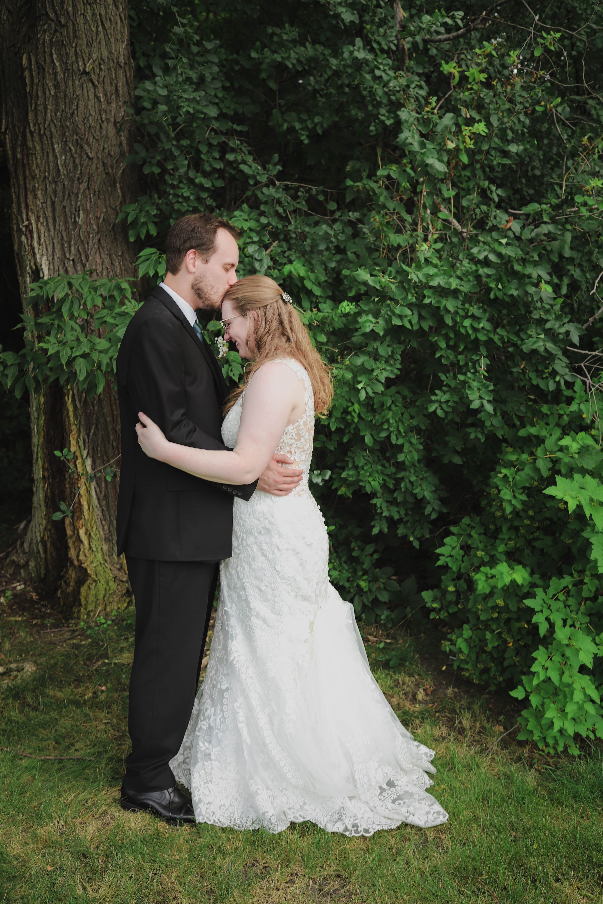 Romantic wedding portrait against lush green foliage backdrop.