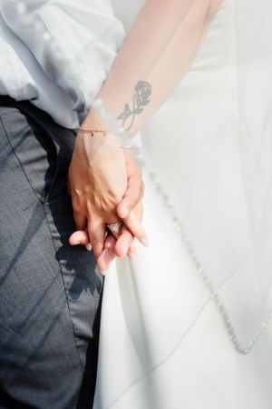 Close-up detail of hands holding white wedding dress fabric.