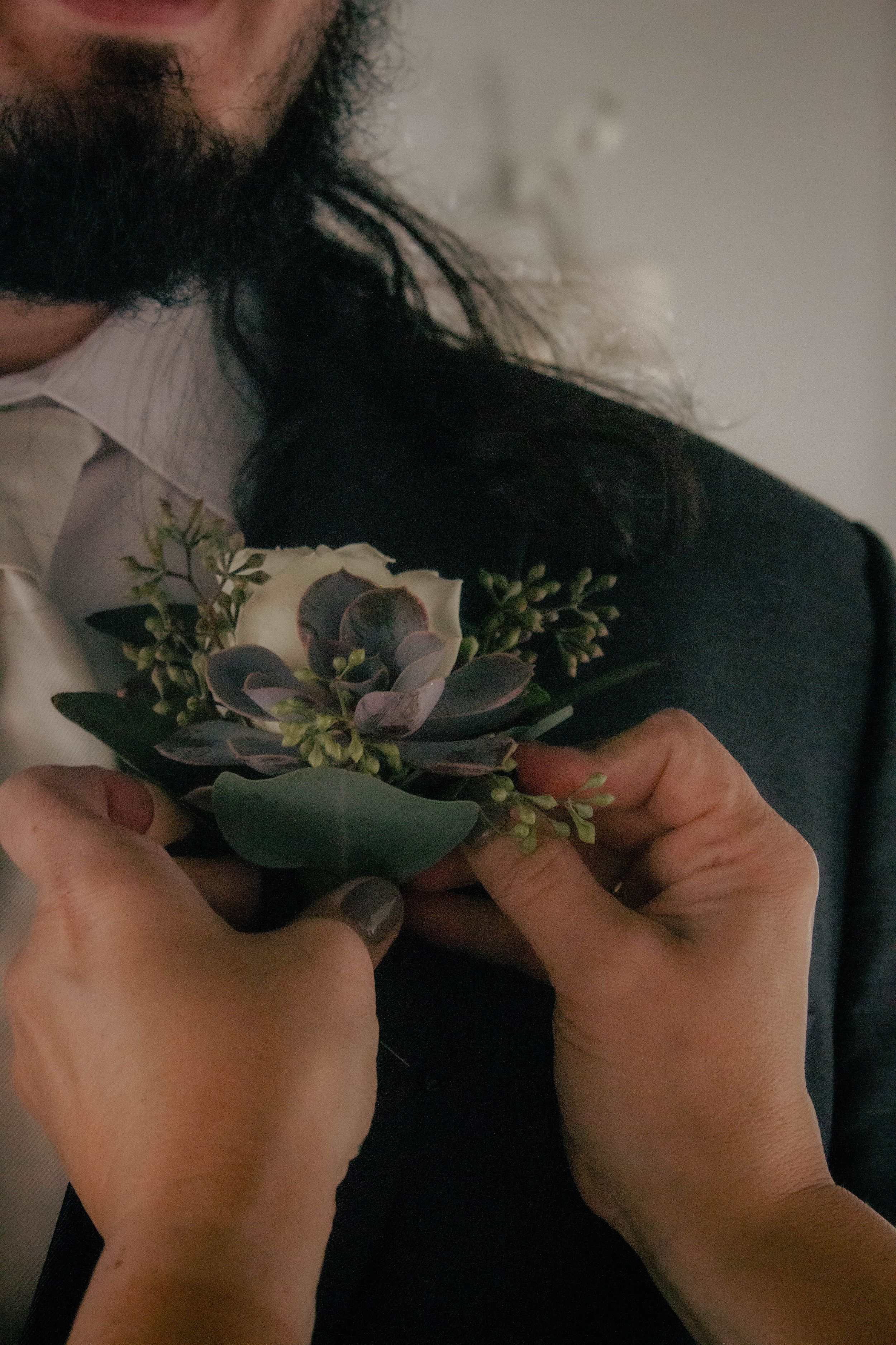 Close-up of black boutonniere accessories with greenery for wedding party members.
