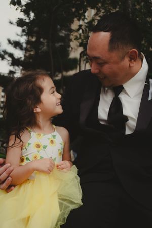 A sweet moment between a child in a yellow floral dress and an adult in formal attire.