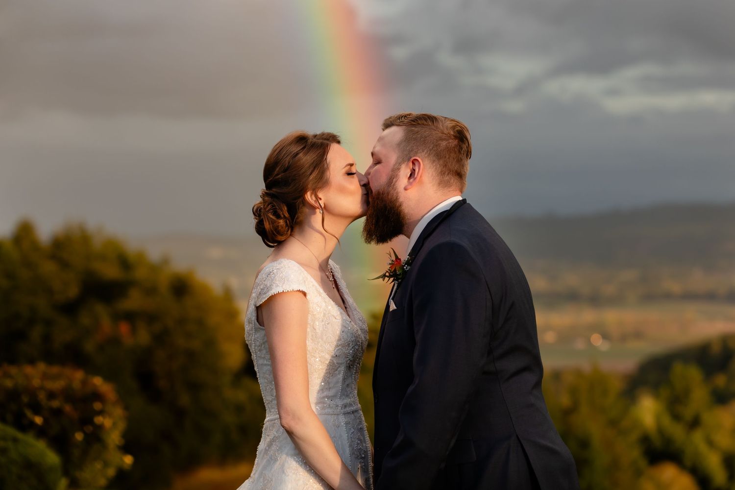 A romantic sunset wedding portrait with a rainbow glowing in the stormy background.