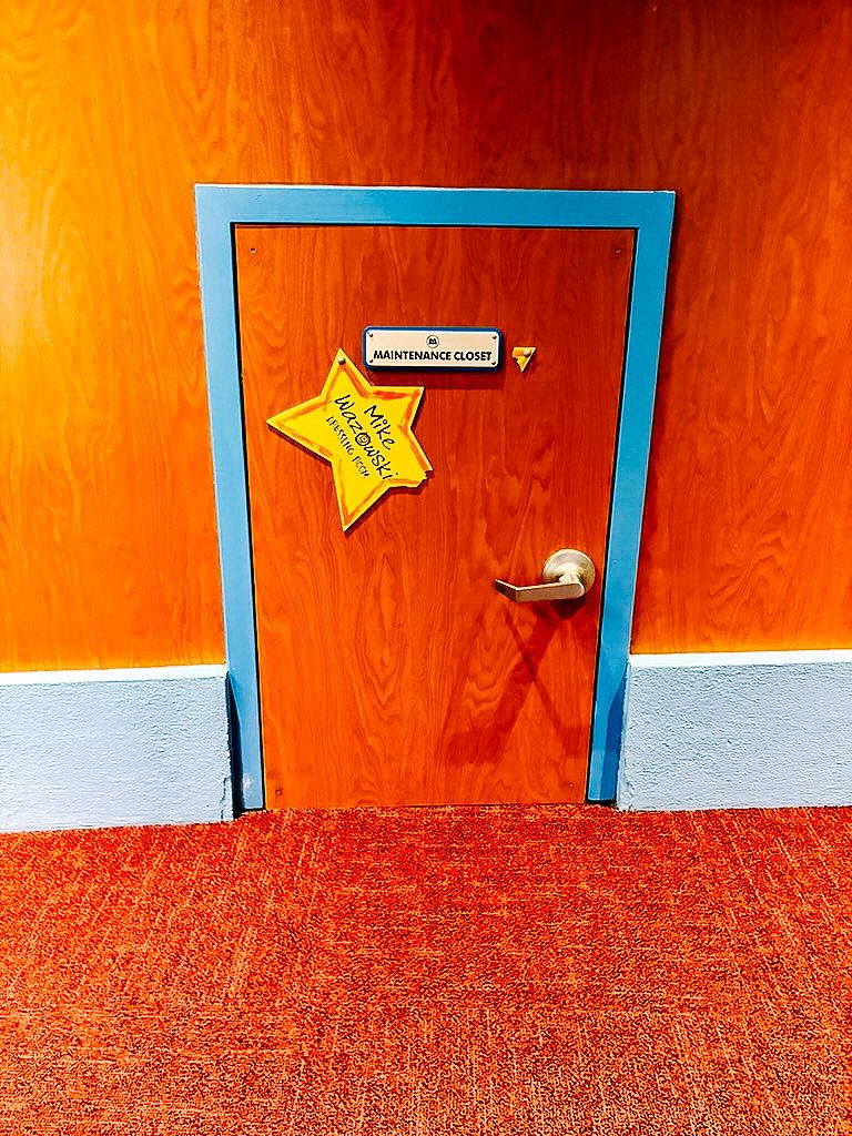 A blue-framed door with a yellow star decoration on an orange wall with matching orange carpet.