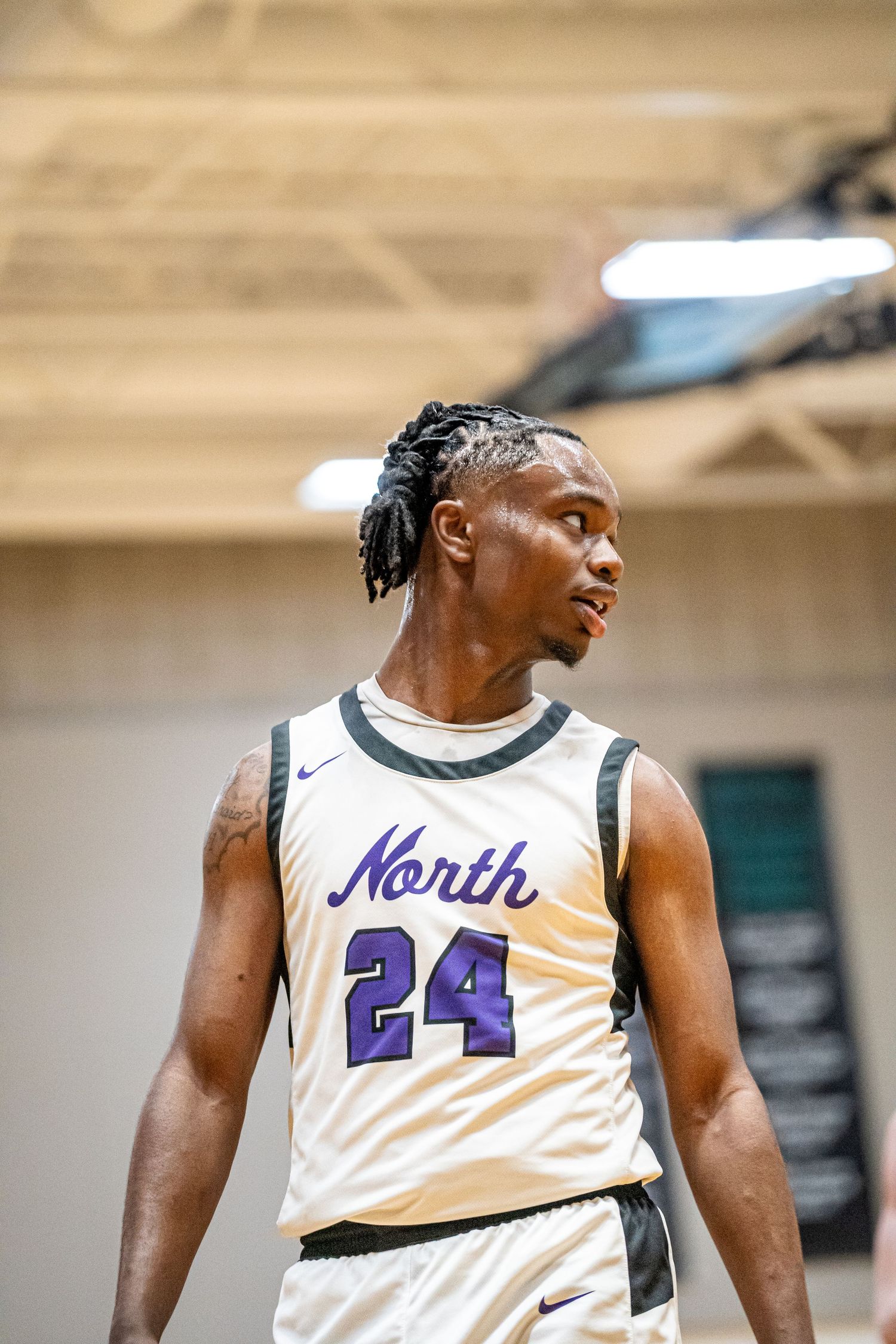 A basketball player wearing a white jersey with number 24 and 'North' text in purple stands on the court during a game.