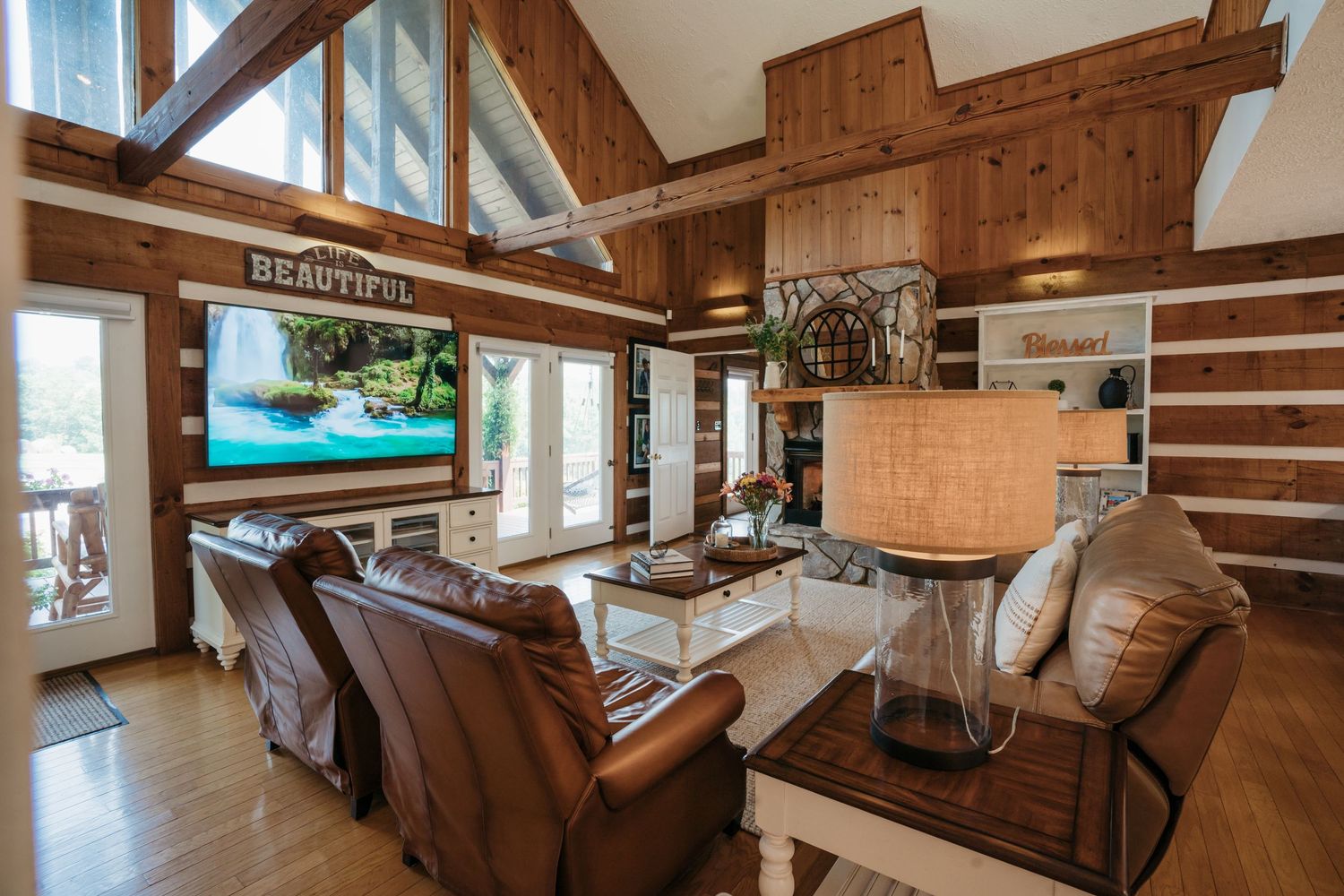 Rustic log cabin interior with exposed beams and large mounted TV.