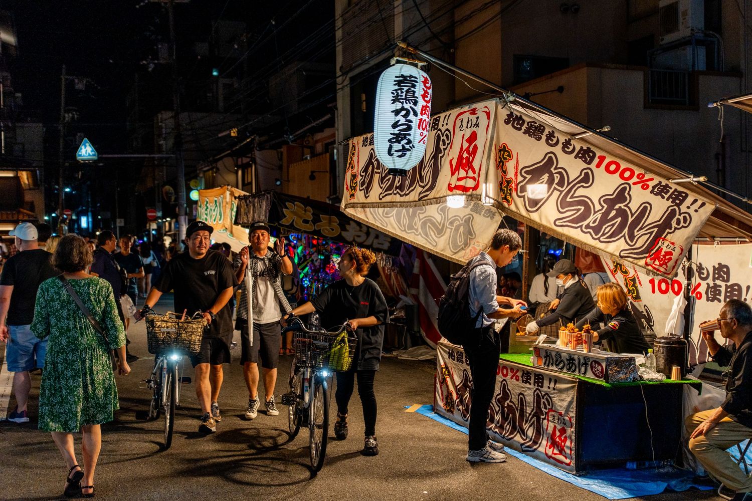 Night market scene in Japan with food stalls and lanterns attracting visitors.