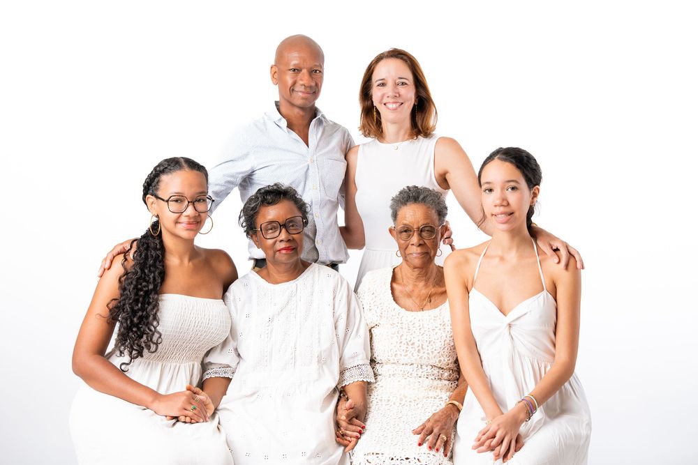 Group of people wearing white clothing standing and posing together against a white background.