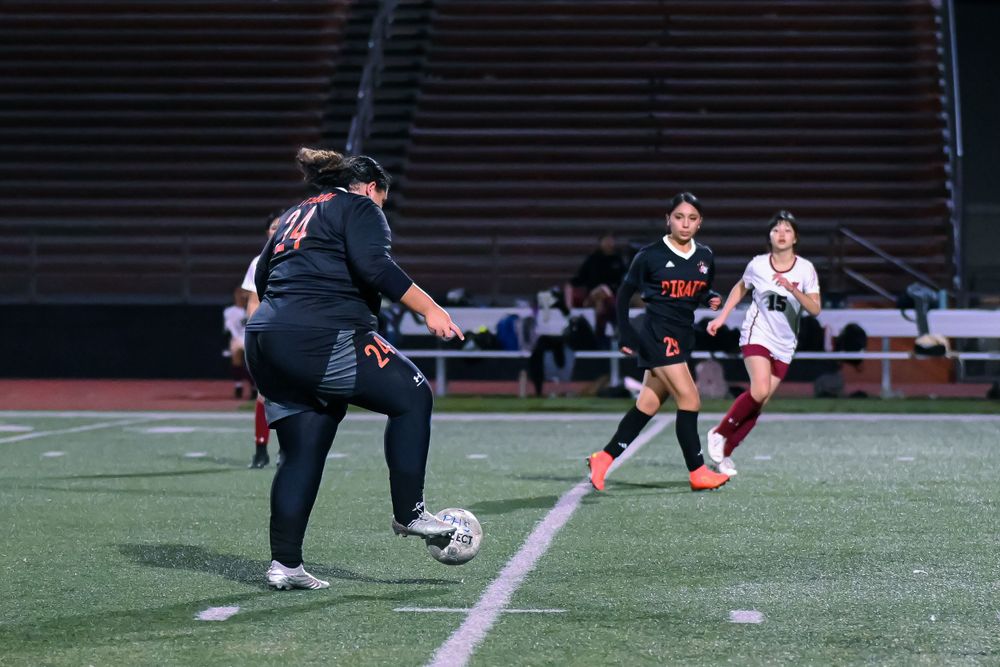 Soccer players compete for ball possession during intense nighttime match action.