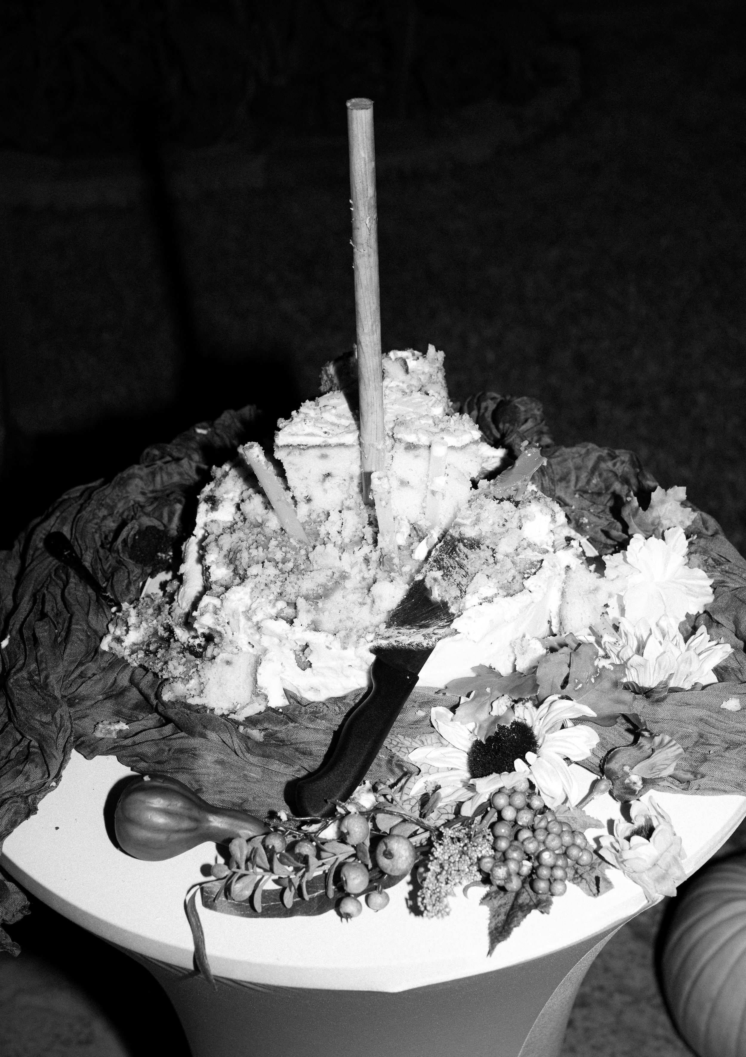 A black and white image of an elaborate wedding cake with decorative toppings.