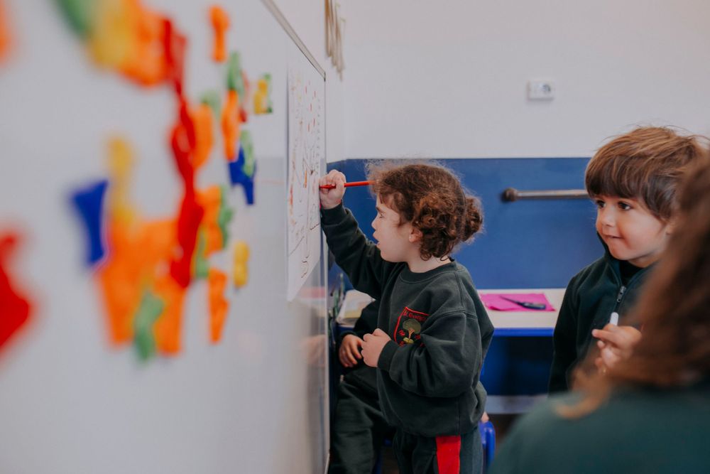 Students interact with vibrant learning materials posted on a classroom wall with colorful pieces and displays.