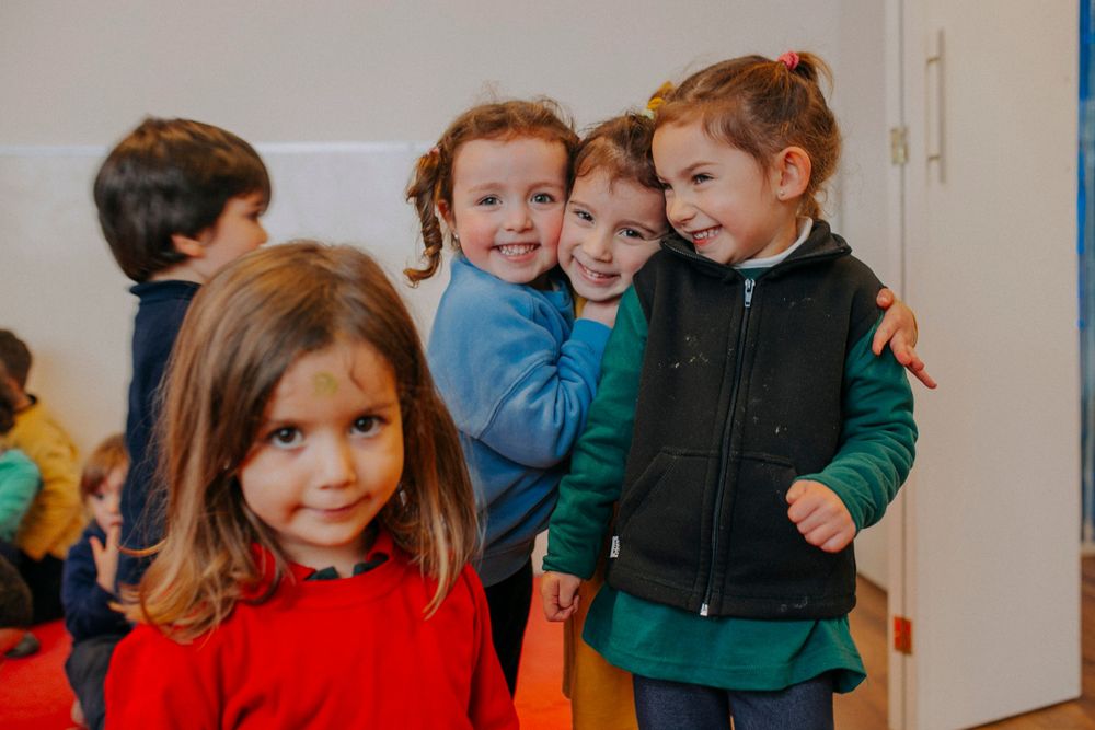 Group of young children laughing and playing together in a classroom setting.