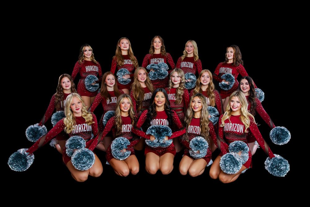 Group of volleyball players in red uniforms pose with blue volleyballs for team photo shoot.
