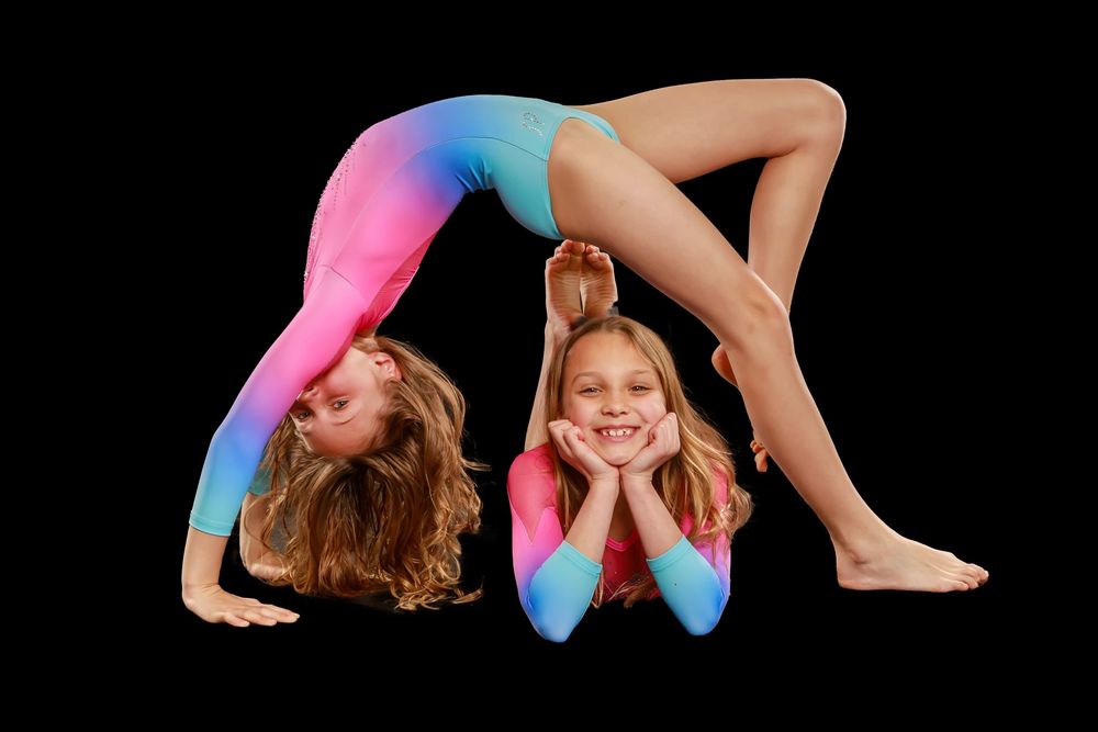A dancer in a colorful leotard performs a graceful sequence of movements against a black background.