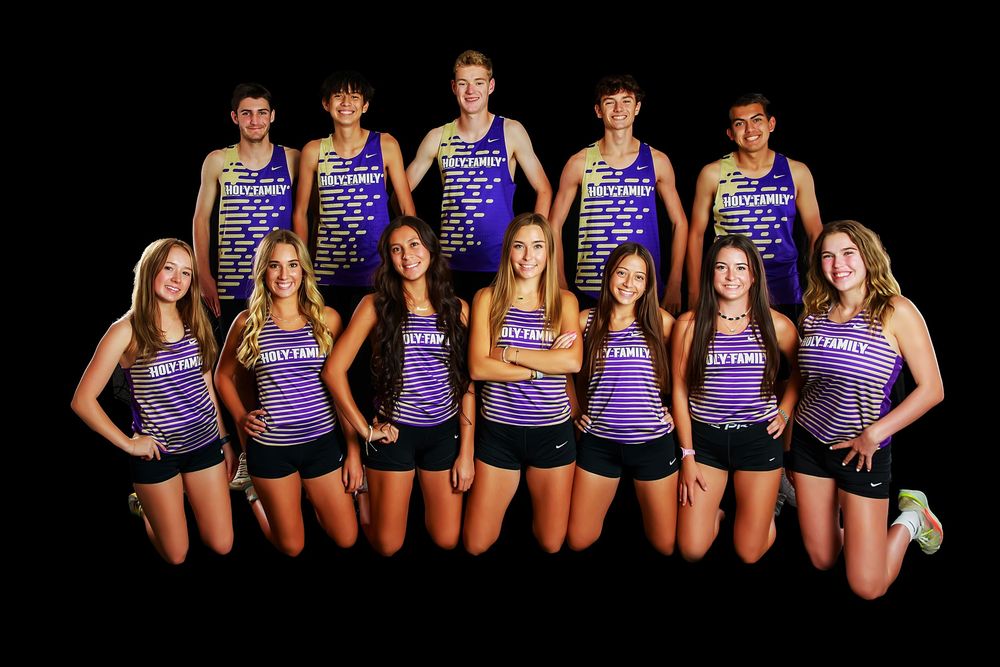 Group of volleyball players wearing matching purple jerseys pose together for team photo on dark background.